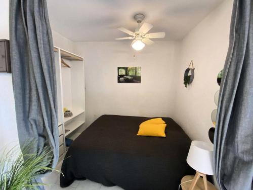 um quarto com uma cama preta e uma almofada amarela em Résidence Pinedes Aryana - 4 Pièces pour 6 Personnes 754 em Six-Fours-les-Plages