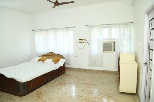 Habitación blanca con cama y ventana en Thiruvallur Farm House, en Tiruvallūr