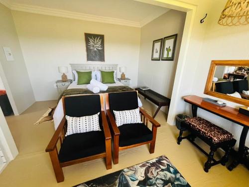 1 Schlafzimmer mit einem Bett mit 2 Stühlen und einem Schreibtisch in der Unterkunft Motubane Guest Farm in Madeteleli