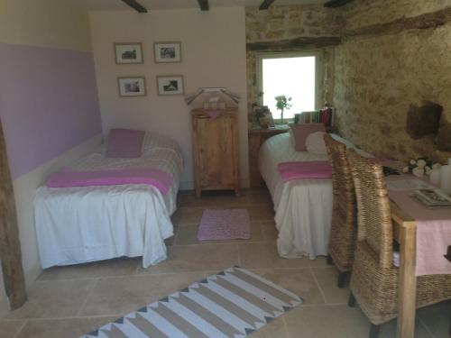 a bedroom with two beds and a table and a window at Lo Petit Cretsou in Simeyrols