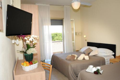 a hotel room with two beds and a flat screen tv at Hotel Lanzoni in Cervia