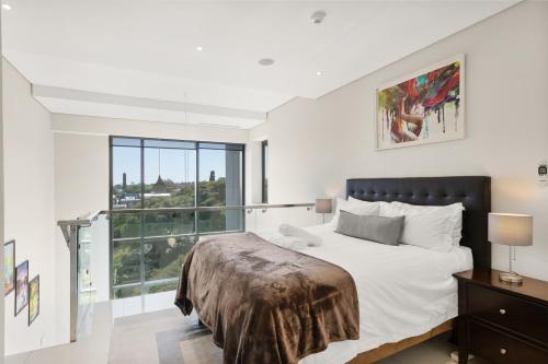 1 dormitorio con cama y ventana grande en Park Central Loft Apartment in Rosebank, en Johannesburgo