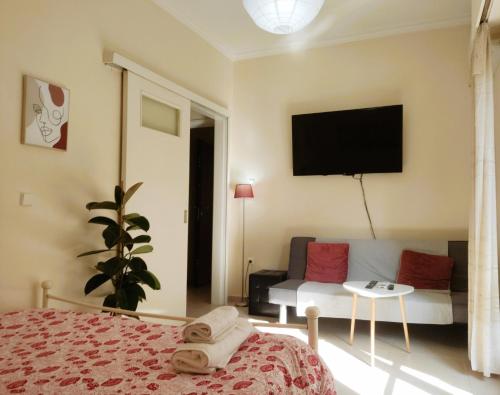 a bedroom with a bed and a couch and a tv at Next to Metro! Bright Apartment with Fully Equipped Kitchen in Athens