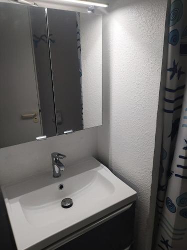 La salle de bains est pourvue d'un lavabo avec miroir et d'un rideau de douche. dans l'établissement Village Moliets - maeva Home - Appartement 3 Pièces 7 Personnes - Sélection MAE-2750, à Moliets-et-Maa