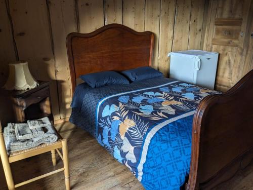 a bedroom with a bed with a blue comforter and a refrigerator at Savoie, Simple mais confortable in Villard-sur-Doron