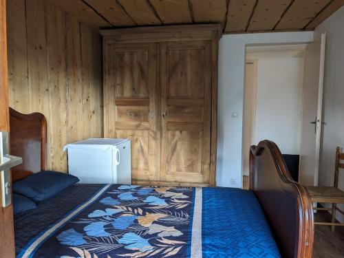 a bedroom with a bed and a refrigerator and a door at Savoie, Simple mais confortable in Villard-sur-Doron