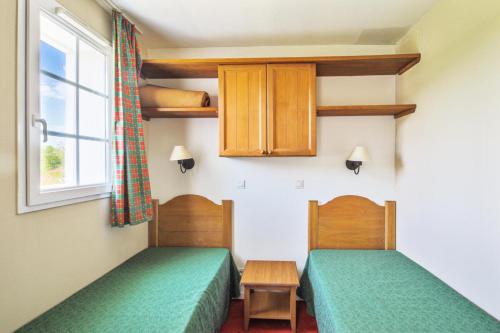 two twin beds in a room with a window at Résidence Le Hameau du Lac - maeva Home - Appartement 2 Pièces 4 Personnes - Budget MAE-2695 in Marciac