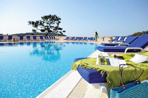 - une piscine avec des chaises bleues et de l'eau dans l'établissement Résidence L'Ange Gardien - maeva Home - Studio 5 Personnes - Confort MAE-2979, à Villefranche-sur-Mer