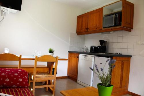 une petite cuisine avec une table et un micro-ondes dans l'établissement Les Chalets De Superd Dauphinelle - 2 Pièces pour 4 Personnes MAE-8134, à Saint-Étienne-en-Dévoluy