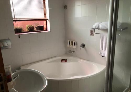 baño blanco con bañera y ventana en A La Martha's Air-Port Guest House, en Port Elizabeth