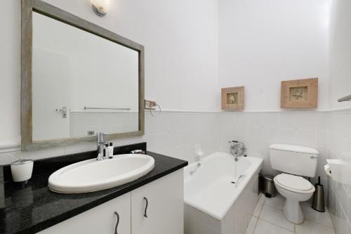 een badkamer met een wastafel, een toilet en een spiegel bij San Lameer Villa 2809 - 3 Bedroom Classic - 6 pax - San Lameer Rental Agency in Southbroom