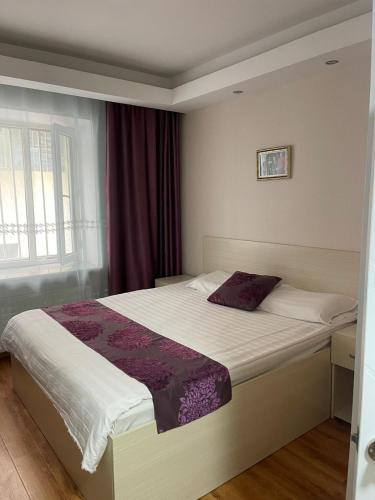 ein Schlafzimmer mit einem Bett mit einer lila Bettdecke in der Unterkunft Mandarin in Ulaanbaatar