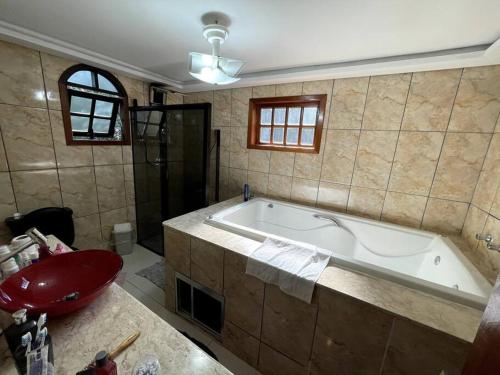 a bathroom with a tub and a red sink and a sink at Chácara em Ibiúna com piscina e acesso a represa in Ibiúna