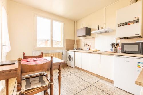 une cuisine avec des armoires blanches, une table et un micro-ondes dans l'établissement Cosy T1 Lavoisier tout équipée avec balcon CL-FD, à Clermont-Ferrand