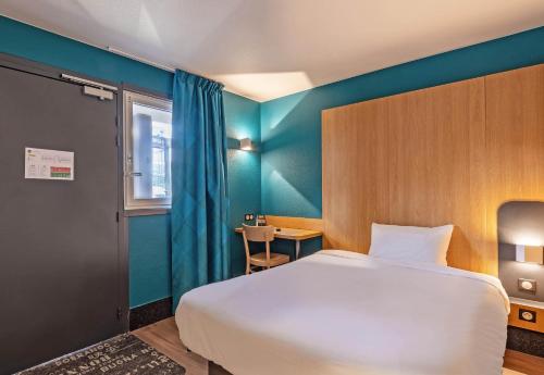 カンペールにあるB&B HOTEL Quimper Nord Douarnenezのベッドルーム1室(白いベッド1台、青い壁付)