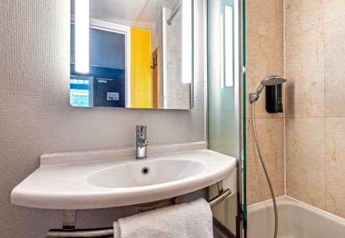 a bathroom with a sink and a mirror and a shower at B&B HOTEL Quimper Nord Douarnenez in Quimper