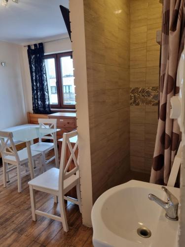 a bathroom with a sink and a table and chairs at Hostel Rumiankowy Airport Hostel in Wrocław