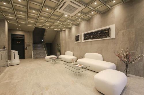 a lobby with white chairs and a table and stairs at H Avenue Hotel Sangmu Branch in Gwangju