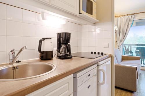 - une cuisine avec un évier et une cafetière sur un comptoir dans l'établissement La Résidence du Golf - maeva Home - Appartement avec balcon 2 pièces 4 personnes - Sélection - super Home MAE-5438, à Deauville