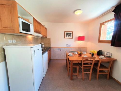 une cuisine avec une table et un réfrigérateur blanc dans l'établissement Résidence Les Toits Du Devoluy - APPARTEMENT 6 PERSONNES BALCON SUD MAE-8514, à Saint-Étienne-en-Dévoluy