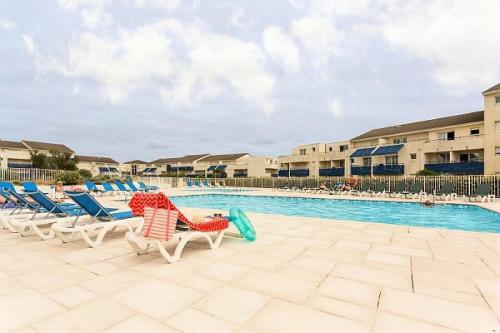 une piscine dans un complexe avec des chaises longues et une piscine dans l'établissement Résidence Bleu Marine - maeva Home - Appartement 3 Pièces 6 Personnes vue mer - Confort MAE-5560, à Lacanau