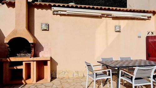 un patio avec une table, des chaises et une cheminée dans l'établissement Appartement Kallisté, Logements avec vue citadelle de Bonifacio, à Bonifacio