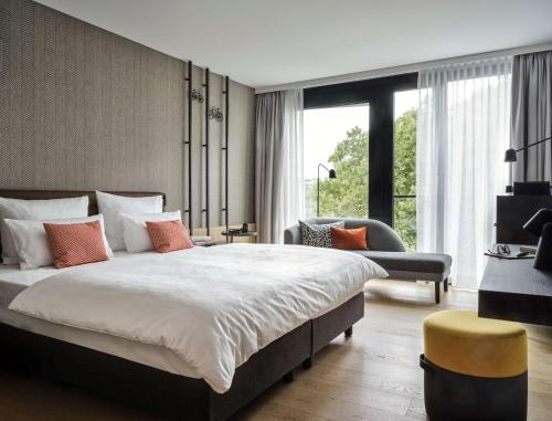 a bedroom with a large bed and a large window at ATLANTIC Hotel Münster in Münster