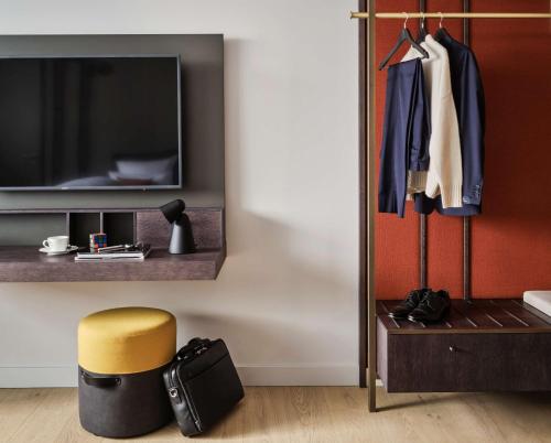 a room with a bed and a tv and a stool at ATLANTIC Hotel Münster in Münster