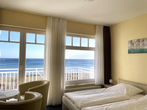 a hotel room with a bed and a view of the ocean at Strandhotel Dünenhaus in Juliusruh