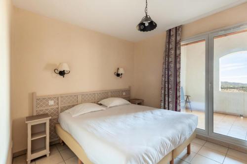 une chambre avec un lit blanc et une grande fenêtre dans l'établissement Les Coteaux de Pont Royal en Provence - maeva Home - Appartement 2 Pièces 4 Personnes - Confort MAE-5993, à Mallemort