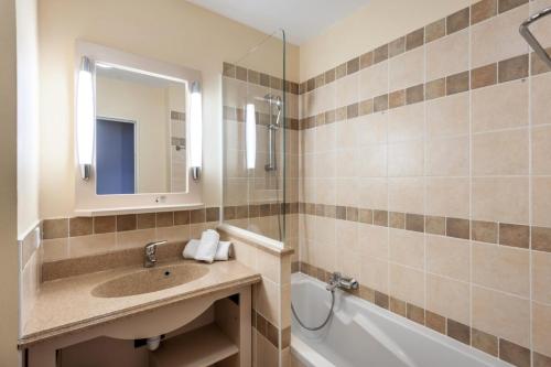 une salle de bain avec un lavabo, une baignoire et un miroir dans l'établissement Les Coteaux de Pont Royal en Provence - maeva Home - Appartement 2 Pièces 4 Personnes - Confort MAE-5993, à Mallemort