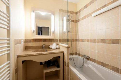 une salle de bain avec un lavabo, une baignoire et un miroir dans l'établissement Les Coteaux de Pont Royal en Provence - maeva Home - Appartement 3 Pièces 6 Personnes - Sélection MAE-6001, à Mallemort
