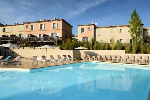 une piscine avec des chaises et un bâtiment dans l'établissement Les Coteaux de Pont Royal en Provence - maeva Home - Maison 4 Pièces 8 Personnes - Budget MAE-6009, à Mallemort