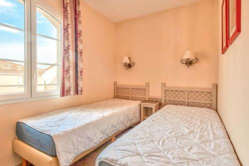 two beds in a room with a window at Les Coteaux de Pont Royal en Provence - maeva Home - Appartement 3 Pièces 6 Per in Mallemort