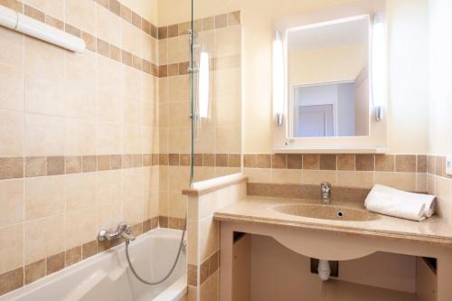 une salle de bain avec un lavabo, une baignoire et un miroir dans l'établissement Les Coteaux de Pont Royal en Provence - maeva Home - Appartement climatisé 2 Pièces 4 Personnes - Sélection MAE-6022, à Mallemort