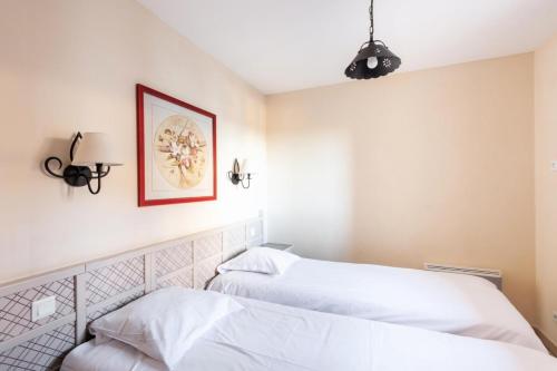 une chambre avec deux lits et un tableau au mur dans l'établissement Les Coteaux de Pont Royal en Provence - maeva Home - Appartement climatisé 2 Pièces 4 Personnes - Sélection MAE-6022, à Mallemort