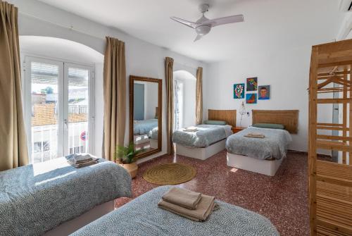 1 dormitorio con 3 camas y espejo en La casa de los marqueses, en Villanueva del Ariscal