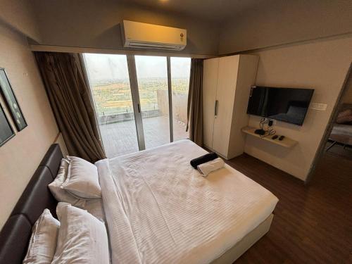 a hotel room with a bed and a large window at Weekend Address By Honest Homes in Surat