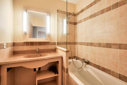 łazienka z umywalką, wanną i lustrem w obiekcie Les Coteaux de Pont Royal en Provence - maeva Home - Appartement 2 Pièces 4 Personnes - Prestige MAE-6030 w mieście Mallemort