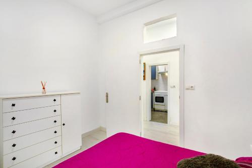 a white bedroom with a pink bed and a dresser at Cristobal y concha in Las Palmas de Gran Canaria