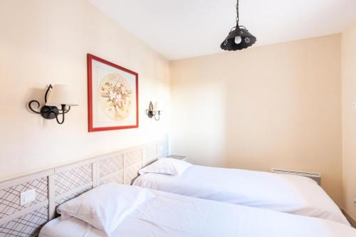 twee bedden in een kamer met witte muren bij Les Coteaux de Pont Royal en Provence - maeva Home - Appartement 2 Pièces 4 16 in Mallemort