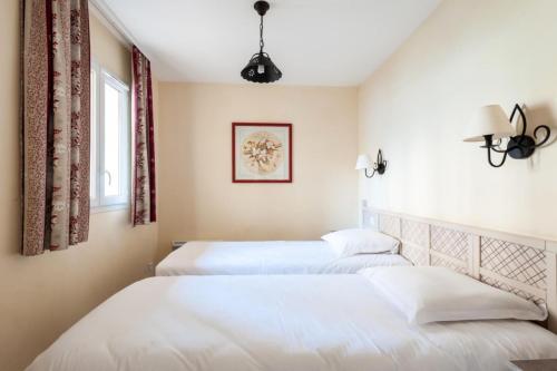 2 bedden in een slaapkamer met witte muren bij Les Coteaux de Pont Royal en Provence - maeva Home - Appartement 2 Pièces 4 17 in Mallemort