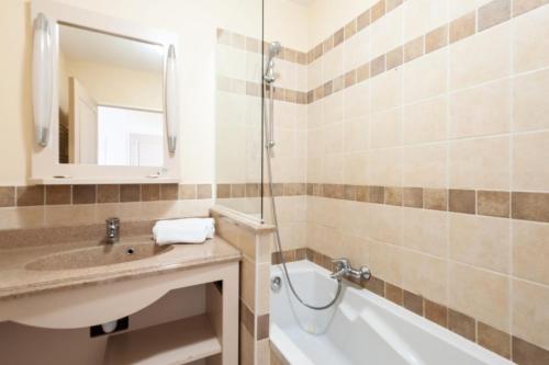 een badkamer met een wastafel, een bad en een spiegel bij Les Coteaux de Pont Royal en Provence - maeva Home - Appartement 2 Pièces 4 17 in Mallemort