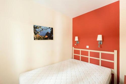 une chambre avec un lit et un mur rouge dans l'établissement Résidence Cannes Villa Francia - maeva Home - Appartement 2 Pièces 4 Personnes - Confort MAE-6043, à Cannes