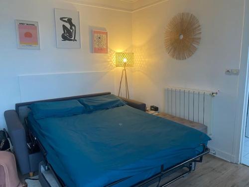 Studio à 3 min du parc des Princes & Roland Garros في باريس: غرفة نوم بسرير ازرق ومصباح
