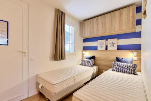 - 2 lits dans une chambre à rayures bleues et blanches dans l'établissement Résidence Port Bourgenay - maeva Home - Studio spacieux 4 personnes - Prestige - super Home MAE-6355, à Talmont-Saint-Hilaire