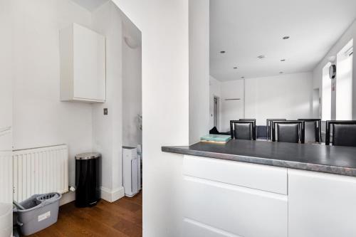 a kitchen with white cabinets and a counter with chairs at Spacious 2 bed Apartment with FREE PARKING for 2 cars and underground station Zone 2 for quick access to Central London up to 8 guests in London