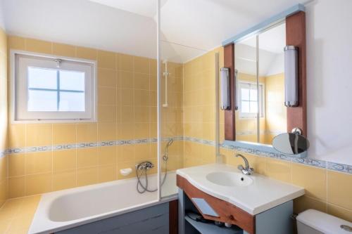 une salle de bain avec un lavabo, une baignoire et un miroir dans l'établissement Les Maisons de Port Bourgenay - maeva Home - Maison 4 pièces 8 personnes - Sélection MAE-6395, à Talmont-Saint-Hilaire