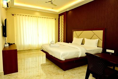 a bedroom with a bed and a desk and a television at DOWNTOWN PR Groups Raashi Residency in Channarāyapatna