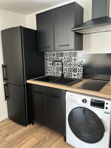 Il comprend une cuisine équipée d'un réfrigérateur noir et d'un lave-linge. dans l'établissement Logement entier Nîmes, à Nîmes